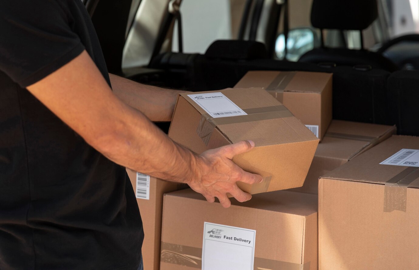 Courier holding shipping boxes in the back of a delivery van